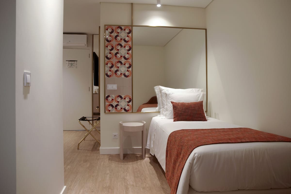 Um quarto moderno com cama, mesa de cabeceira, espelho e guarda-roupa.
