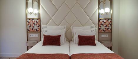 Una cama doble con cabecera capitonada, dos mesitas de noche con lámparas decorativas y una obra de arte mural estampada.