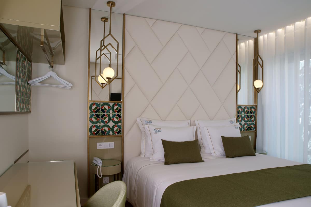 Quarto de hotel com cama, cadeira, escrivaninha, telefone e espelho.