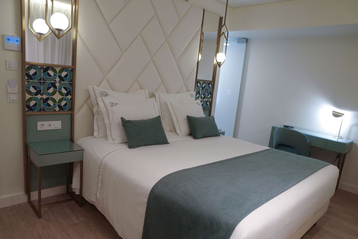 Quarto moderno com uma cama grande, mesas de cabeceira, uma escrivaninha e uma cadeira.
