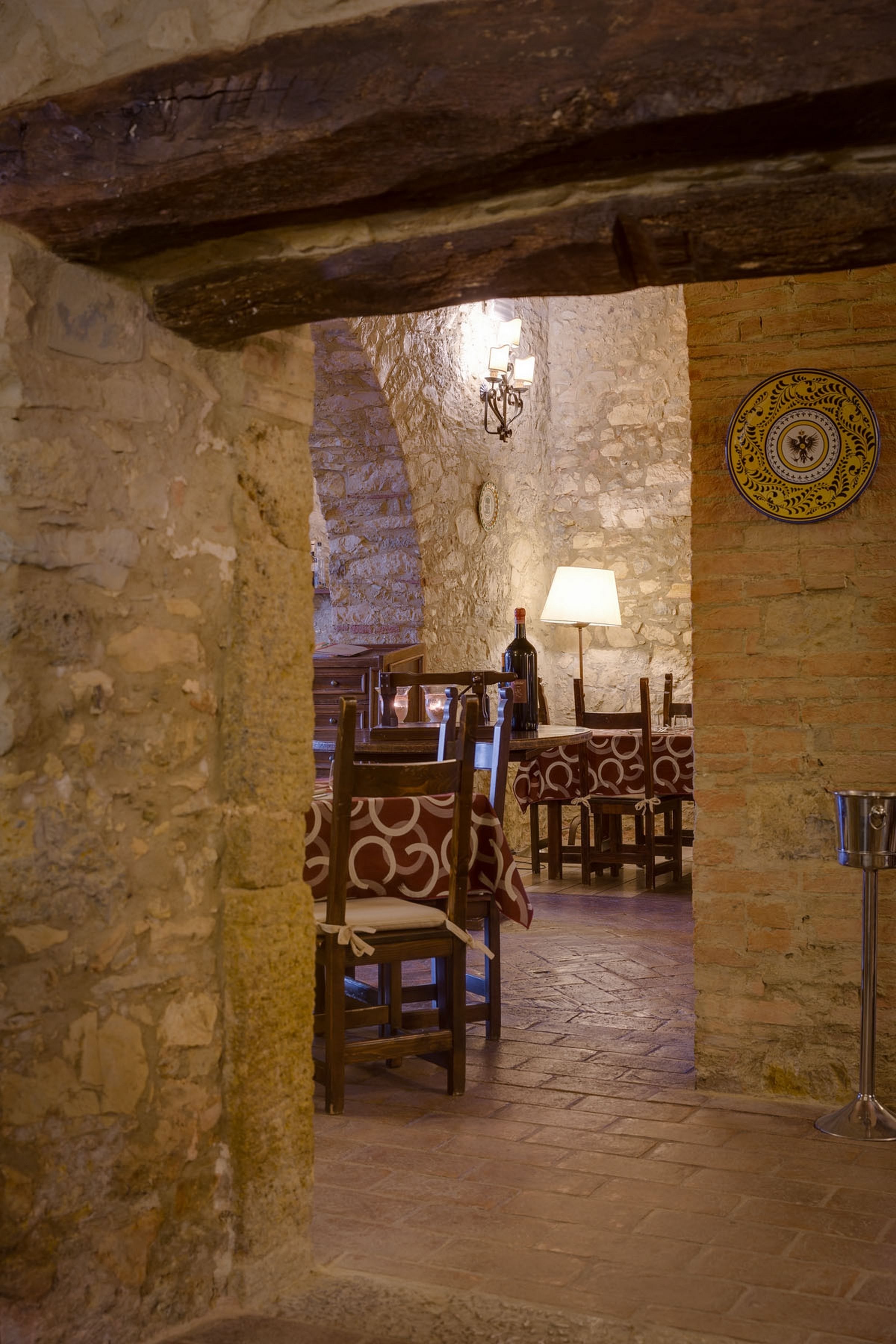 A stone-walled interior with wooden furniture and a table lamp.