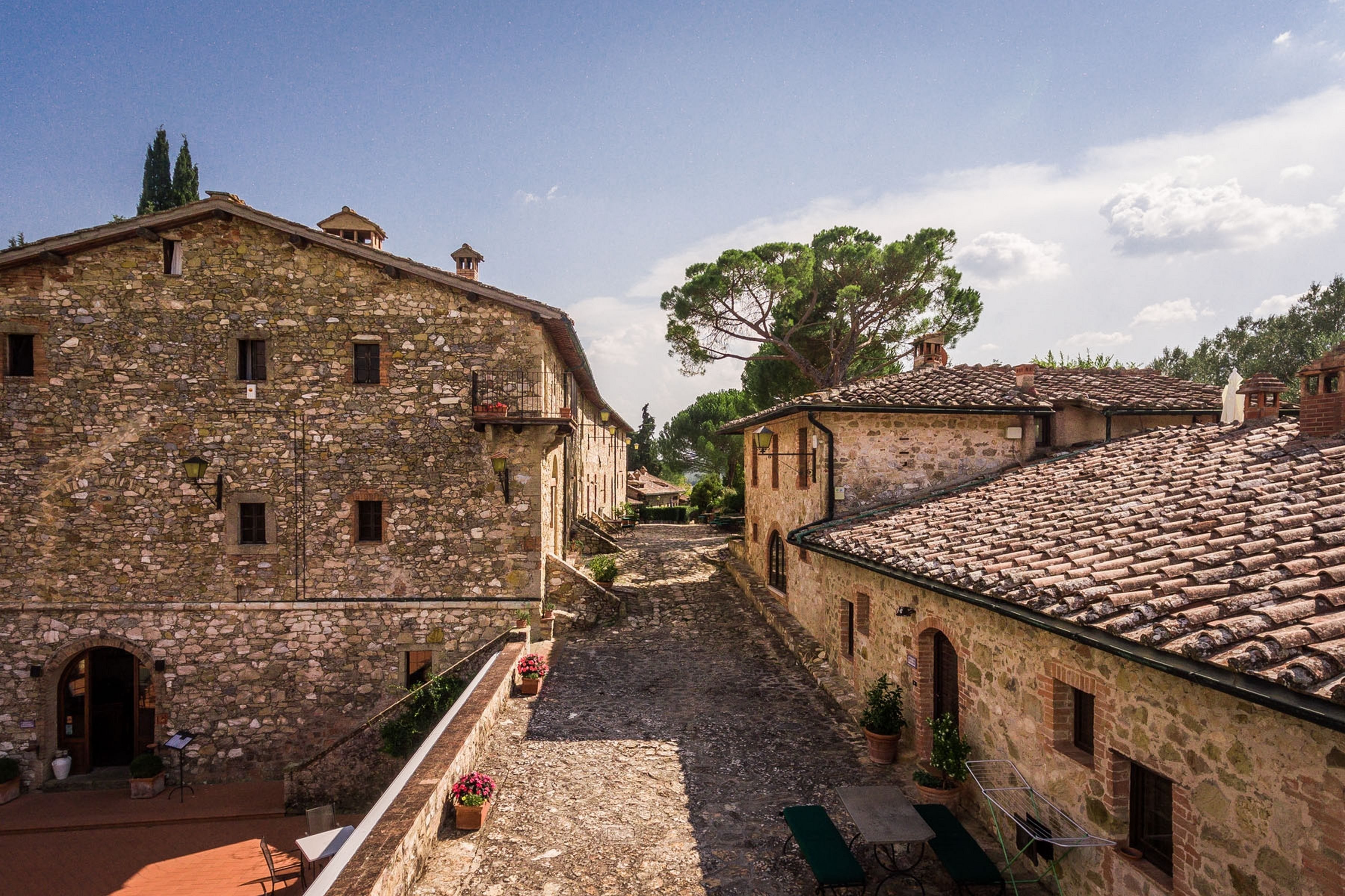 A narrow stone street flanked by traditional buildings with arched doorways and tiled roofs.