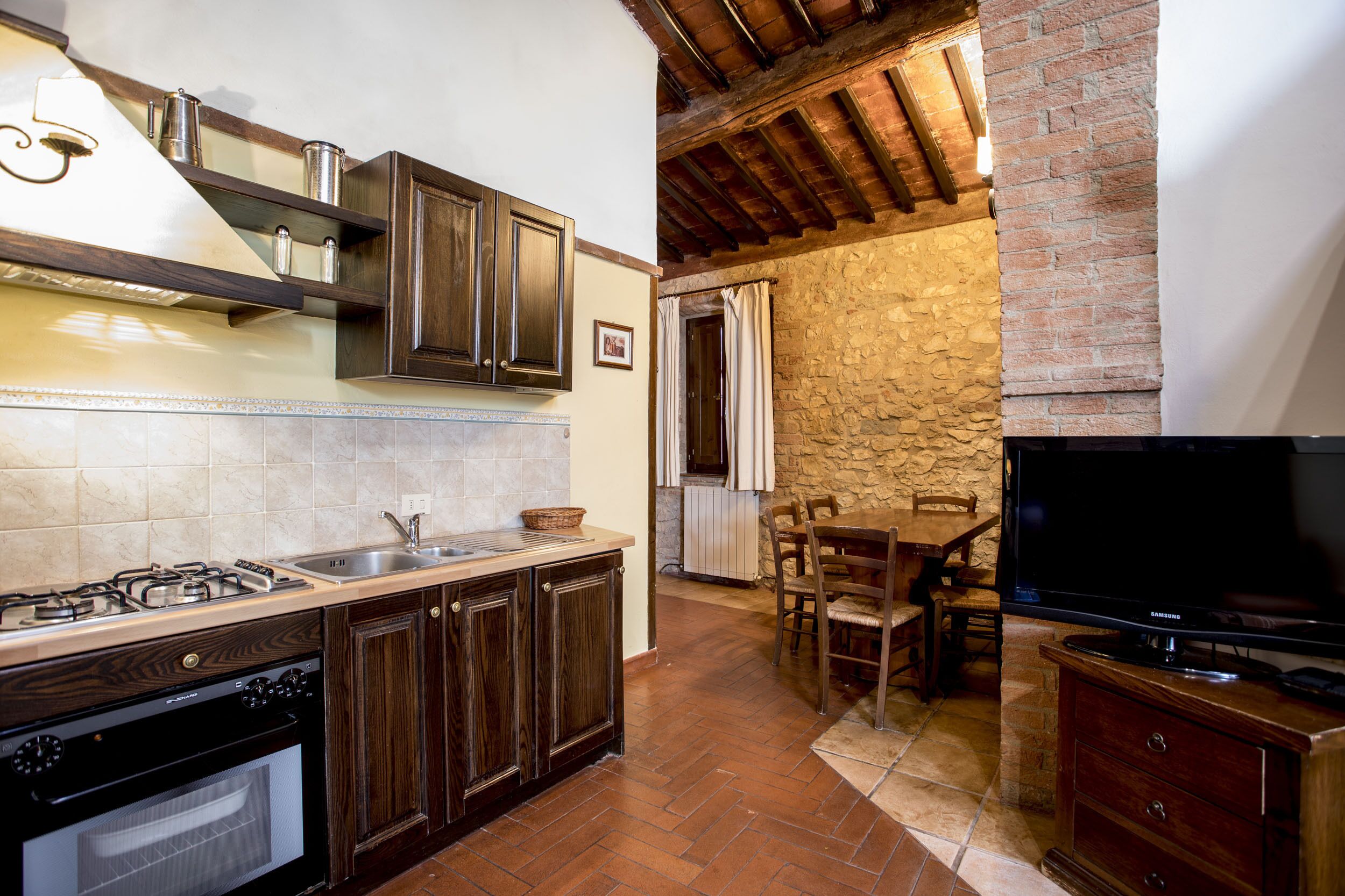 A kitchen with wooden cabinets, a gas stove, and a TV.