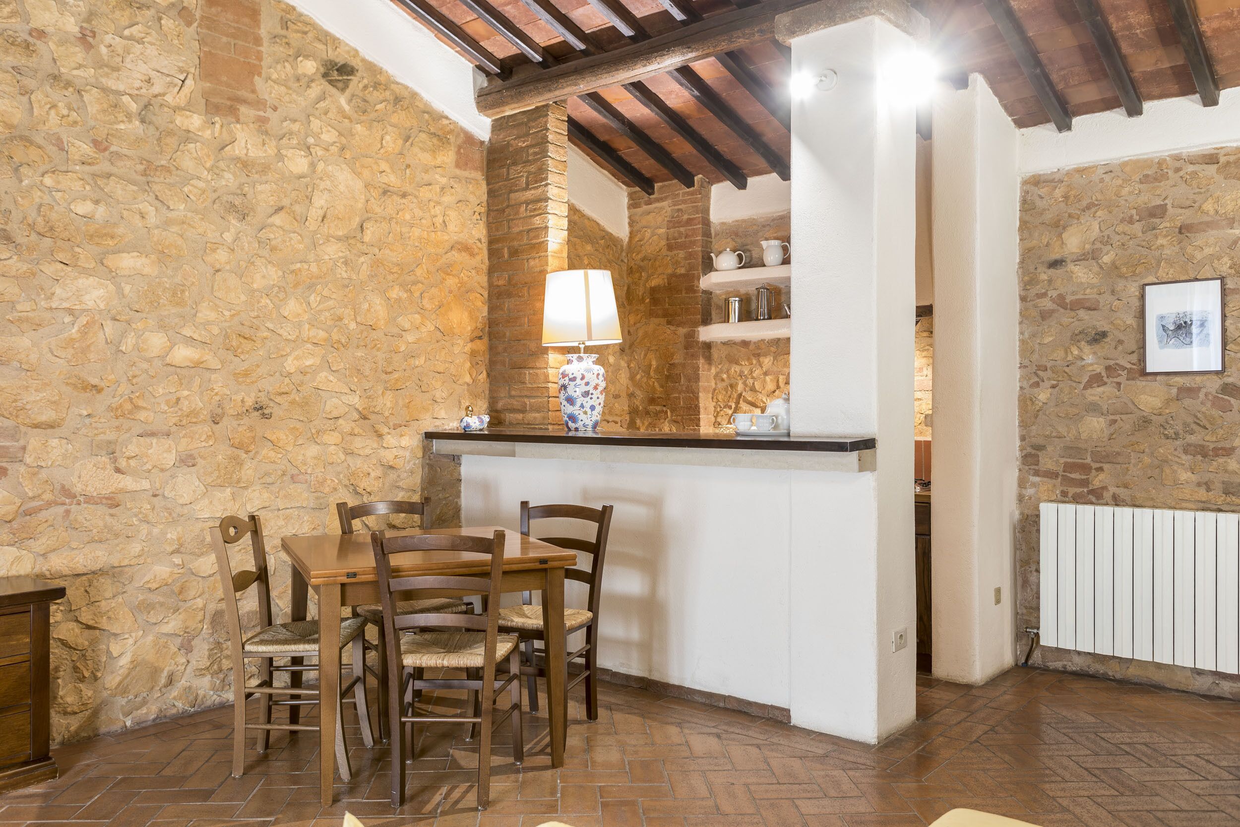 A rustic kitchen with stone walls, a wooden dining table, and a built-in bar area.