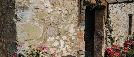 A stone building with a rustic exterior, a wooden door, and a small balcony with a metal railing.