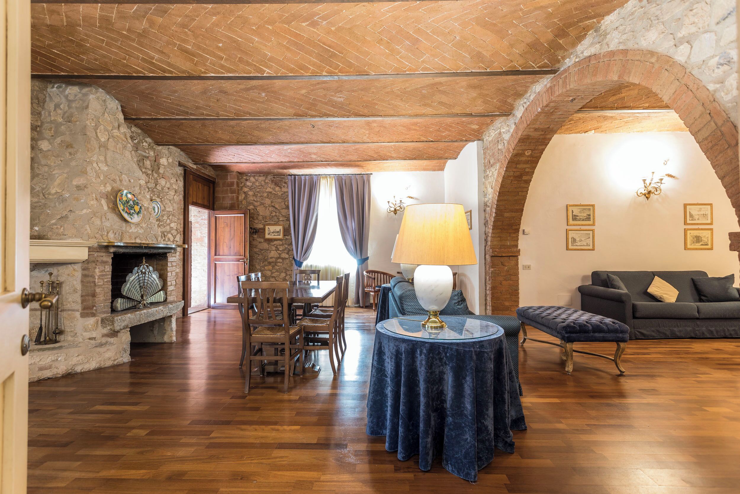 Un interior rústico con chimenea de piedra, muebles de madera y un arco.