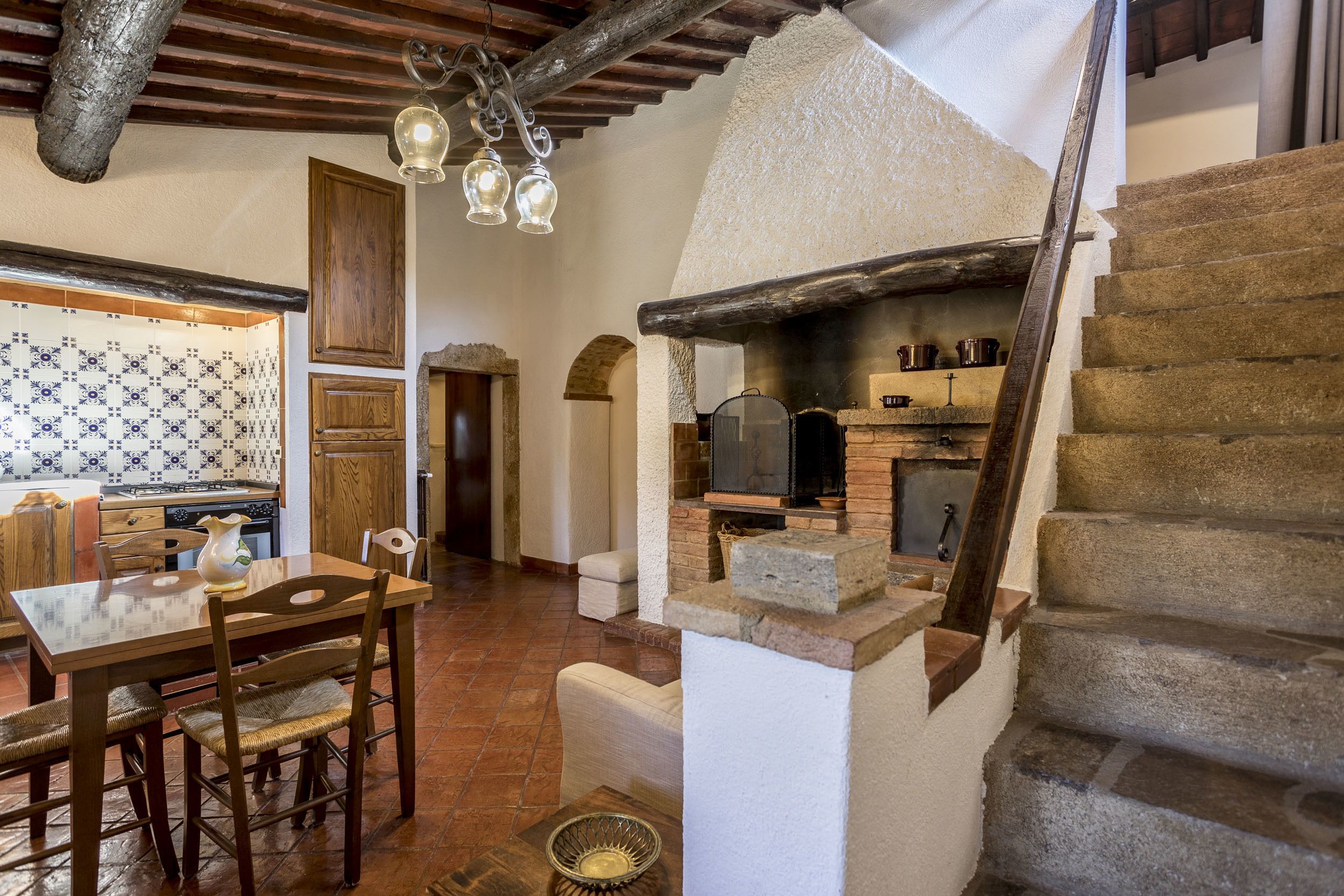 Un intérieur rustique comprenant un coin repas, une cuisine et un escalier.