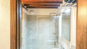 A modern bathroom with a wooden vanity, a white sink, and a glass shower enclosure.