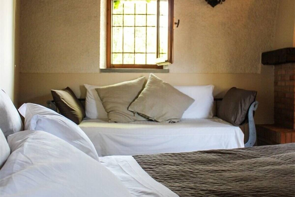 Une chambre avec deux lits, une fenêtre et un luminaire fixé au mur.