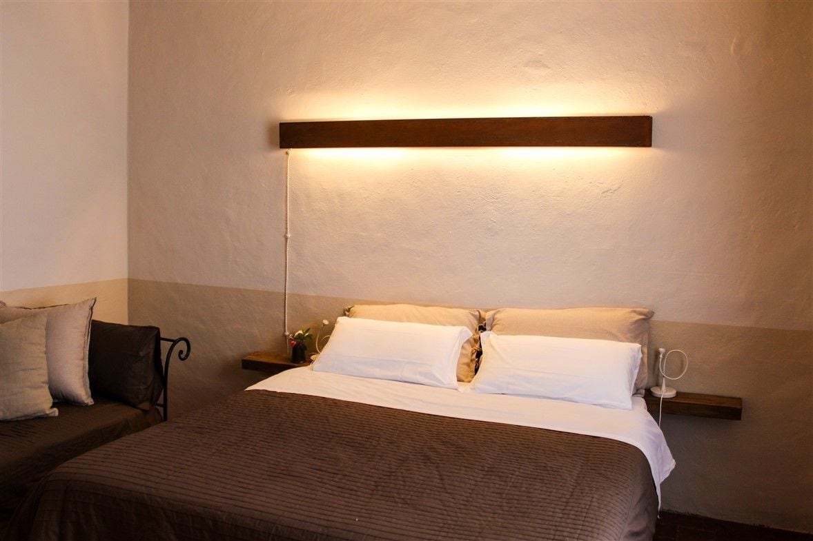 Een hotelkamer met een bed, nachtkastje en een wandlamp.