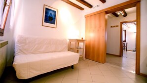 A white sofa in a room with a tiled floor, a wooden door, and a framed picture on the wall. - Bed & Breakfast Giardini (Venice)