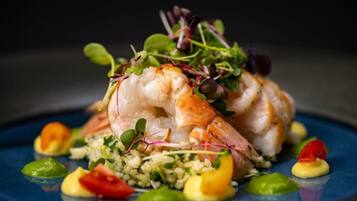 Un plato de comida con camarones, verduras y un plato azul.