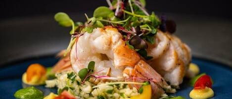 Un plato de comida con camarones, verduras y un plato azul.