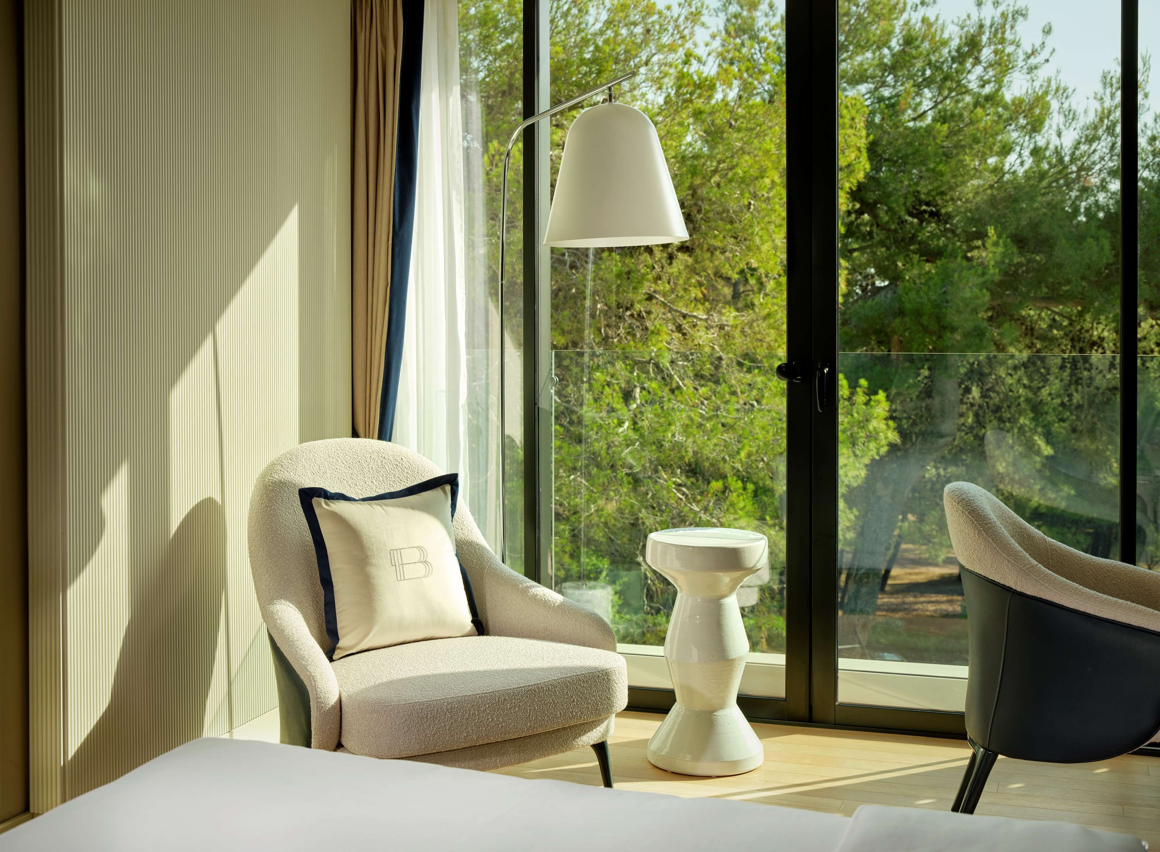 A modern room with a large window, a sofa, a chair, and a floor lamp.