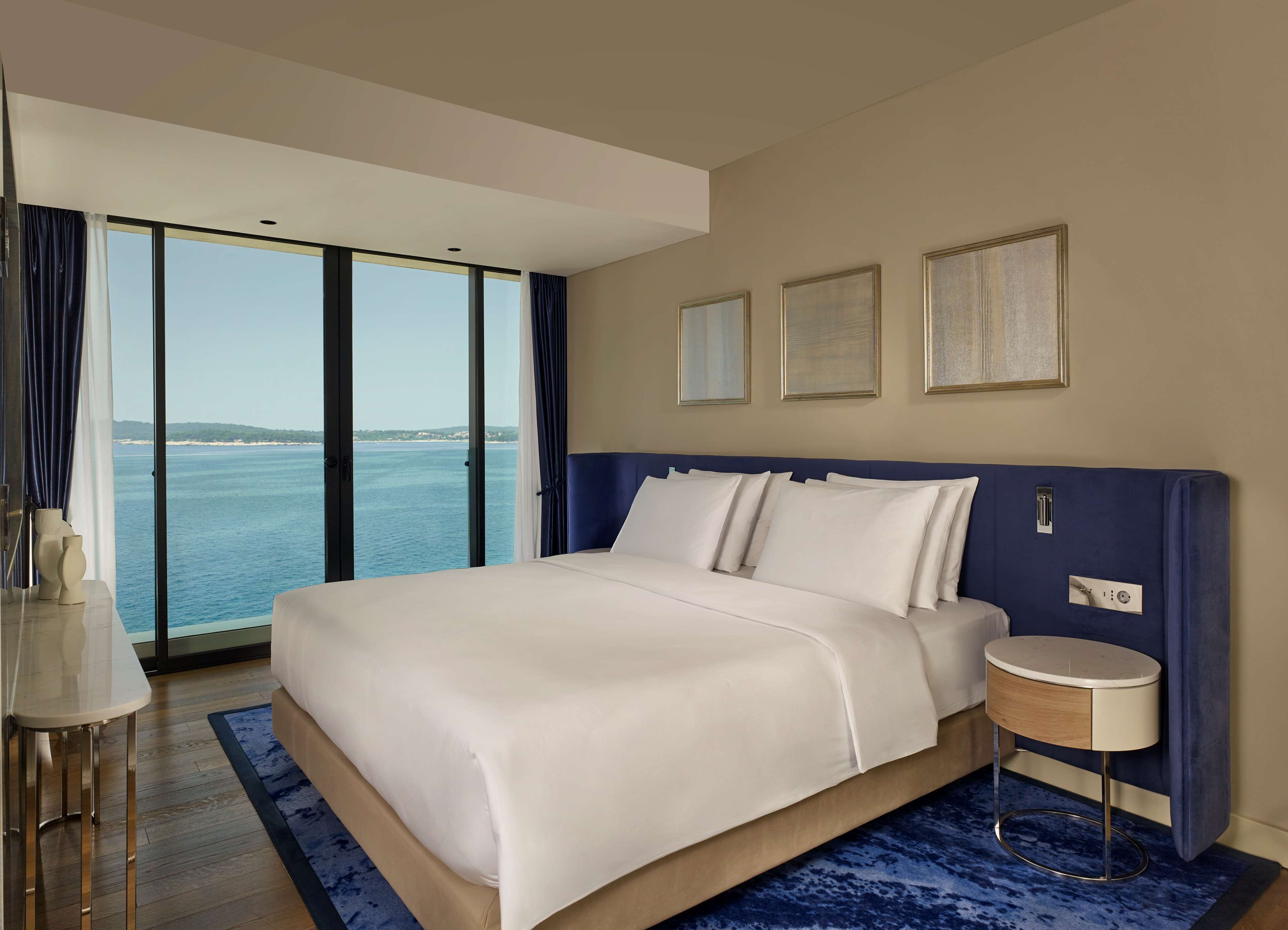 Une chambre d’hôtel moderne avec un grand lit, une table de chevet et une vue sur la mer.