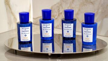 Quatre flacons de produits capillaires Acqua di Parma disposés sur une surface réfléchissante.