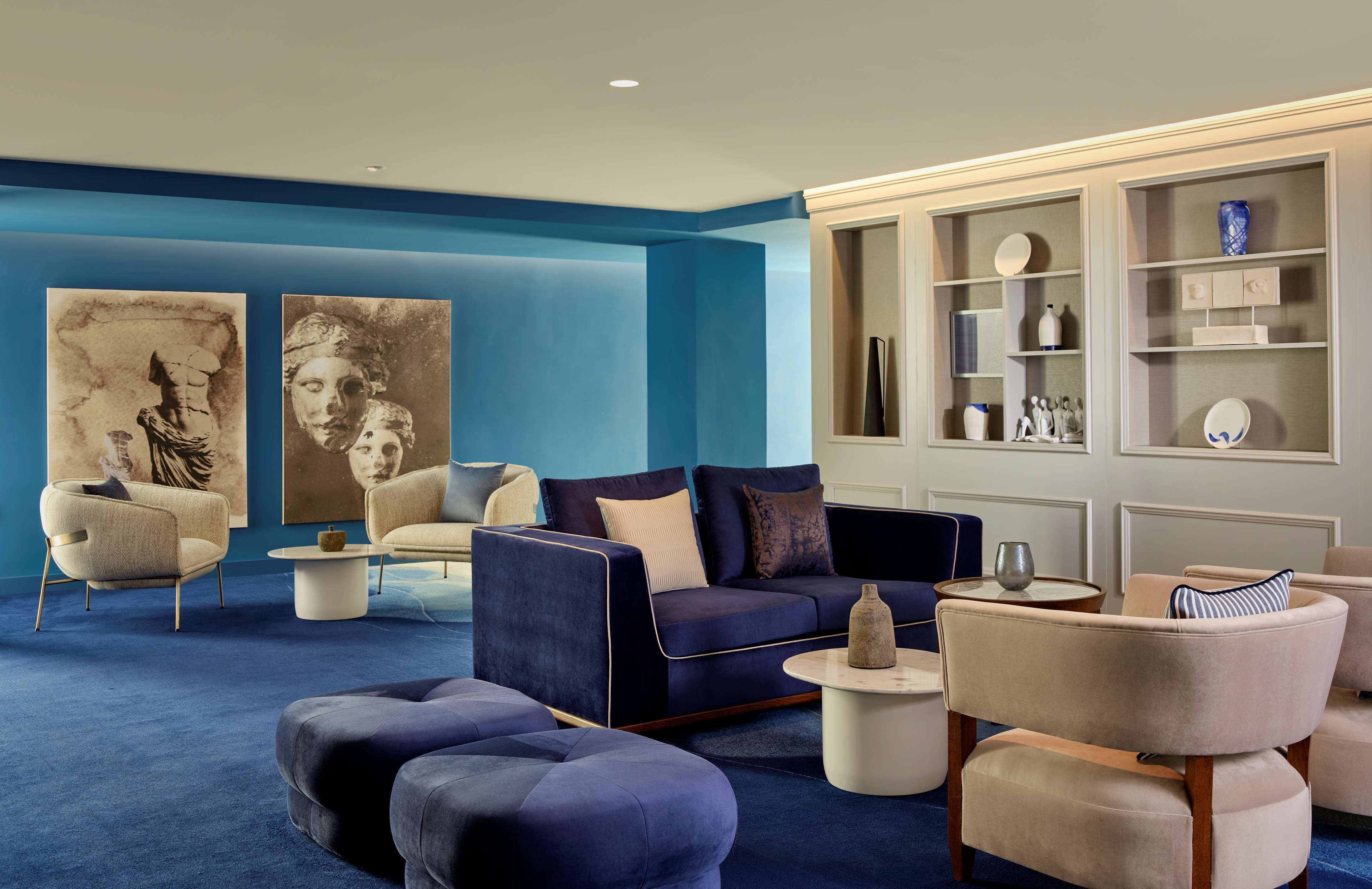Una sala de estar moderna con una pared azul de acento, un sofá azul oscuro, un sillón color beige y una mesa de centro.