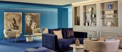 Una sala de estar moderna con una pared azul de acento, un sofá azul oscuro, un sillón color beige y una mesa de centro.
