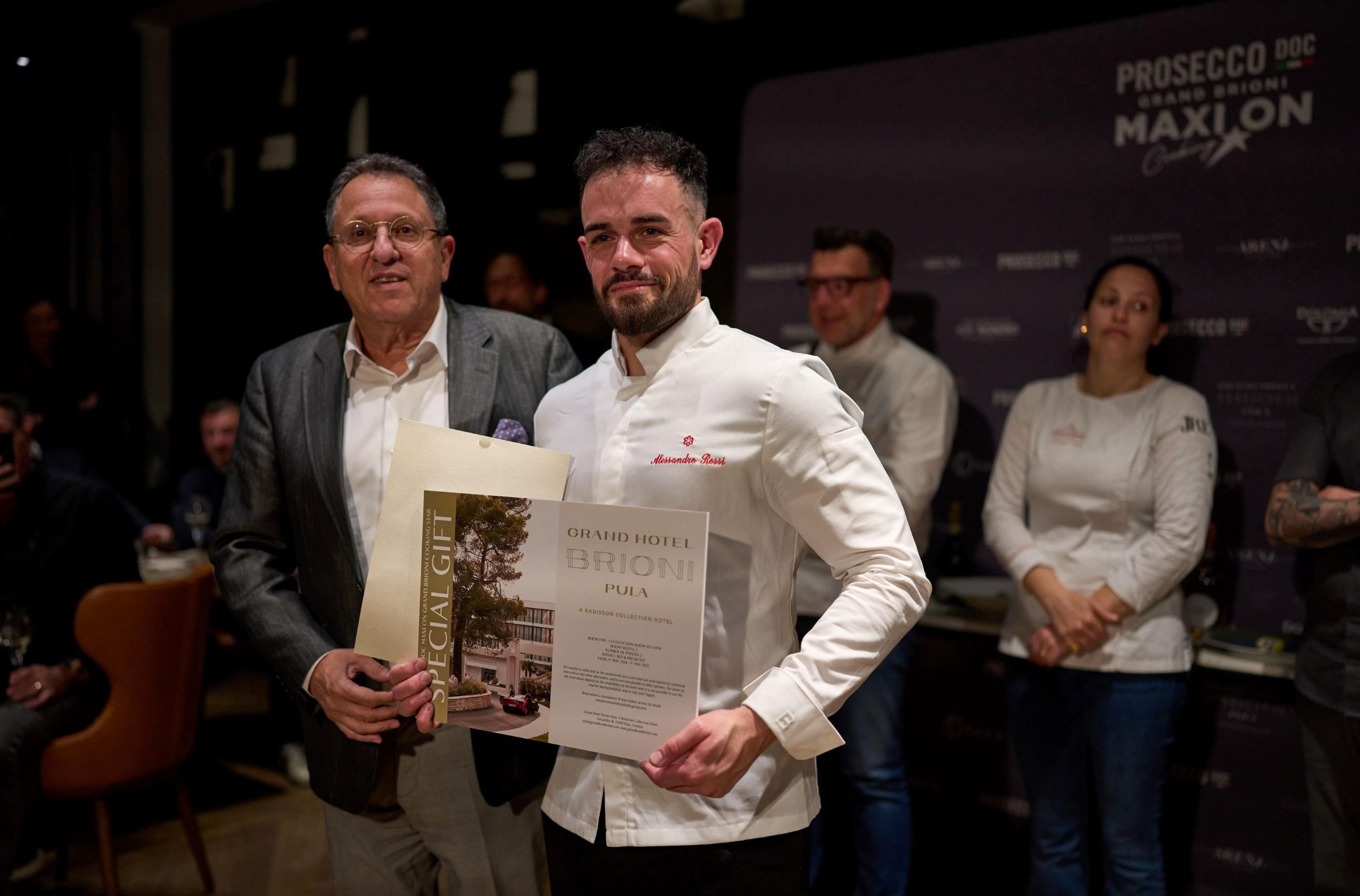 Two men holding a framed document titled "GRAND HOTEL BRIONI PULA".