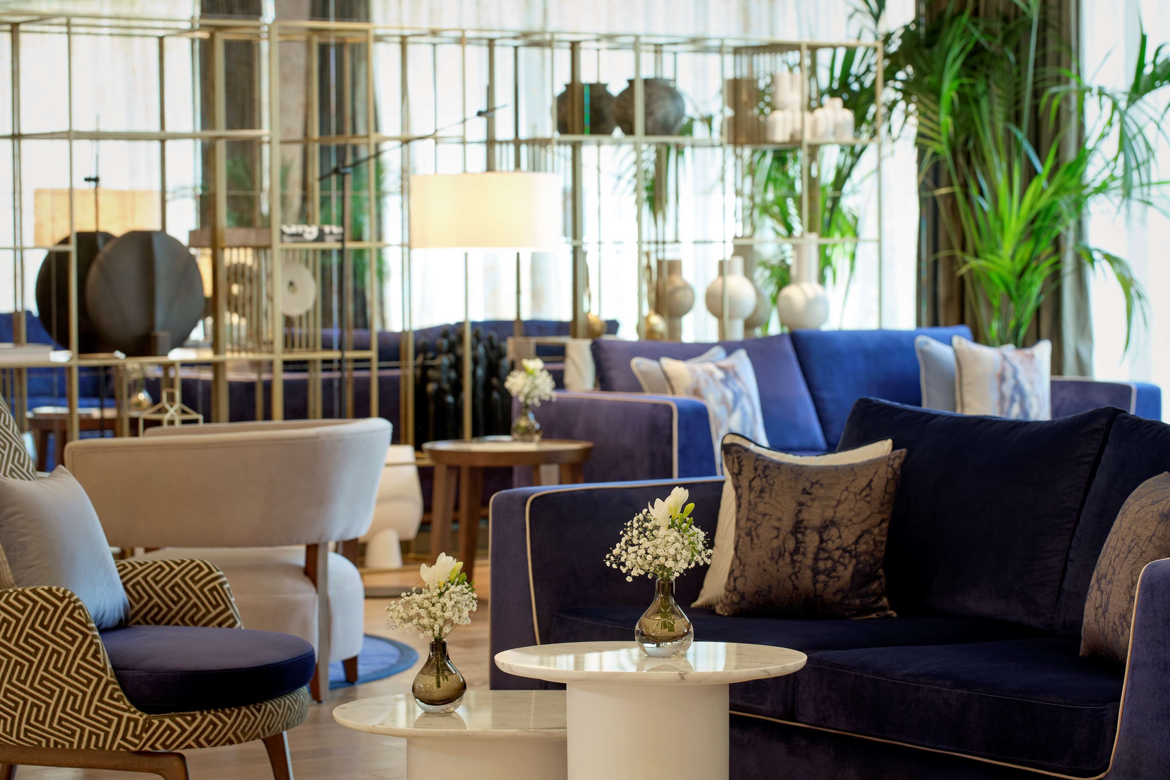 A modern living room with a blue sofa, patterned armchairs, and a coffee table.