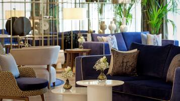 A modern living room with a blue sofa, patterned armchairs, and a coffee table.