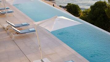 A poolside area with sun loungers and umbrellas, overlooking a body of water.