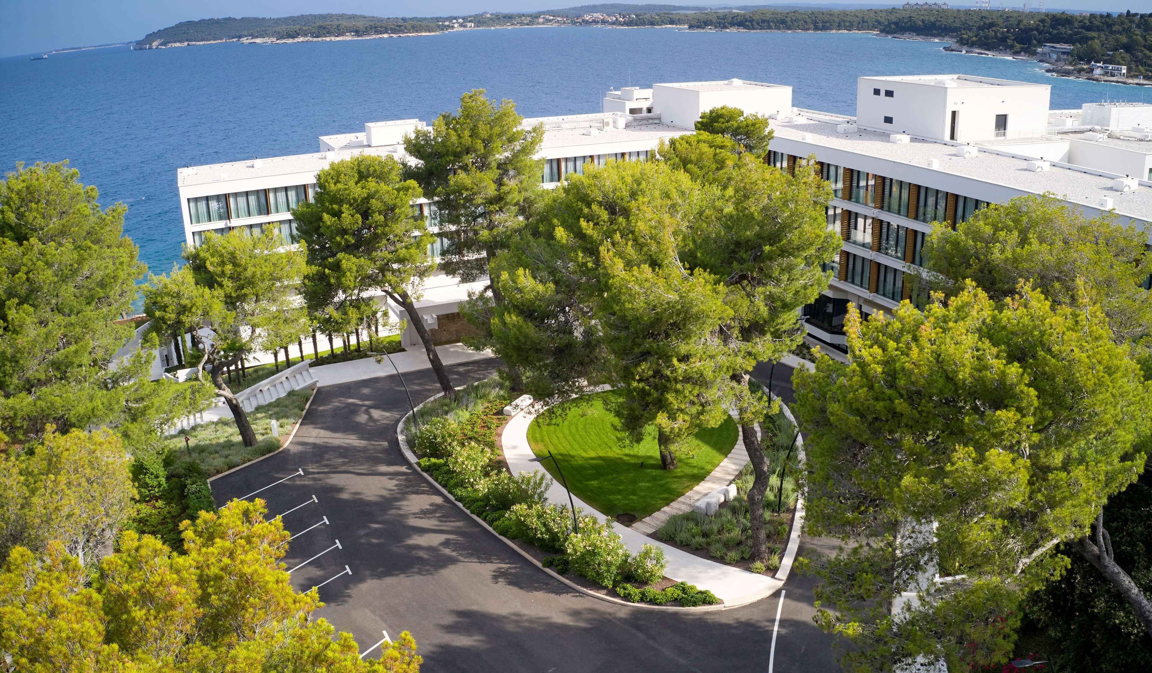 A modern building with a parking lot and a view of the sea.
