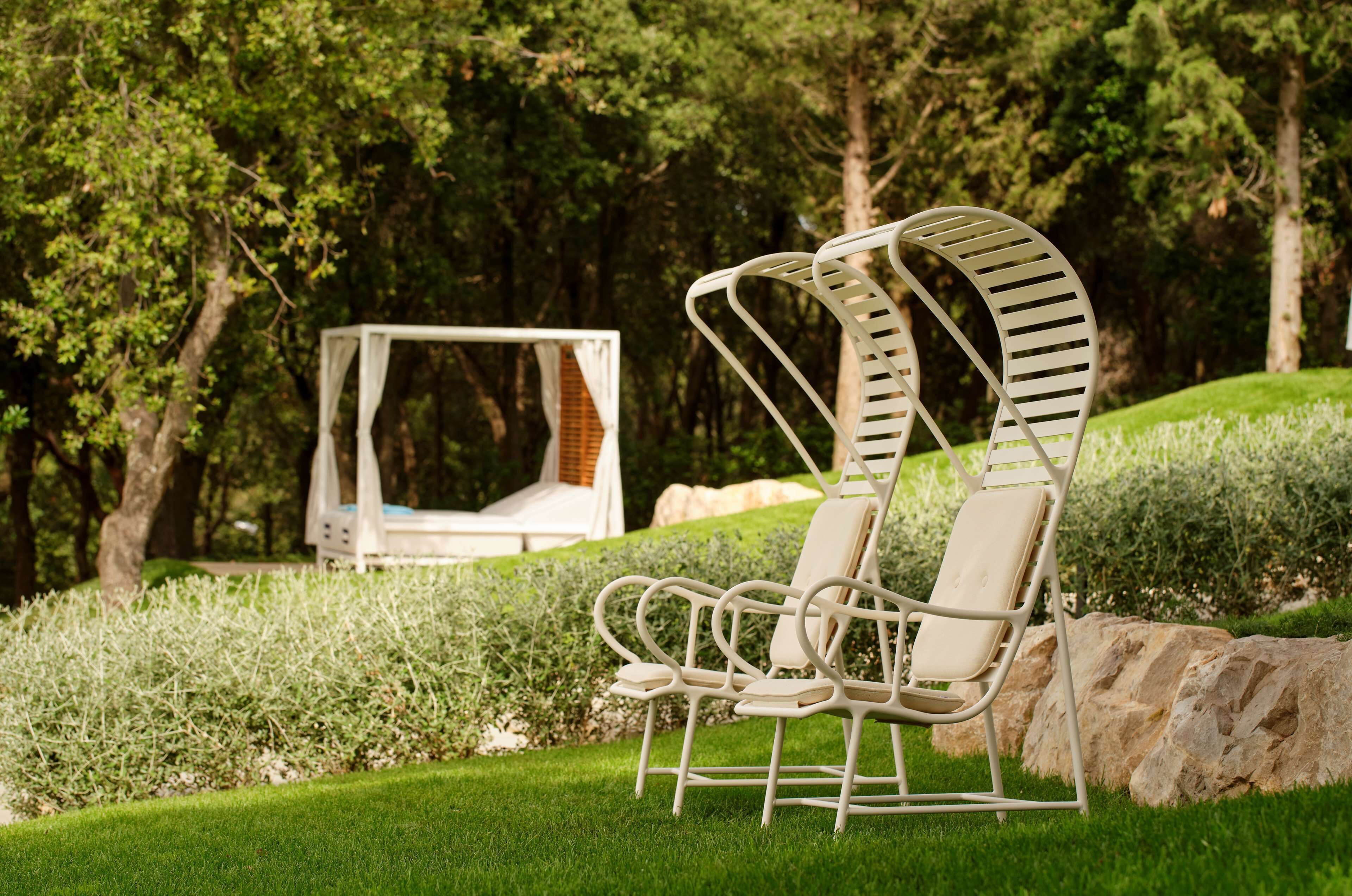 Un jardín con un columpio y dos sillones de descanso.