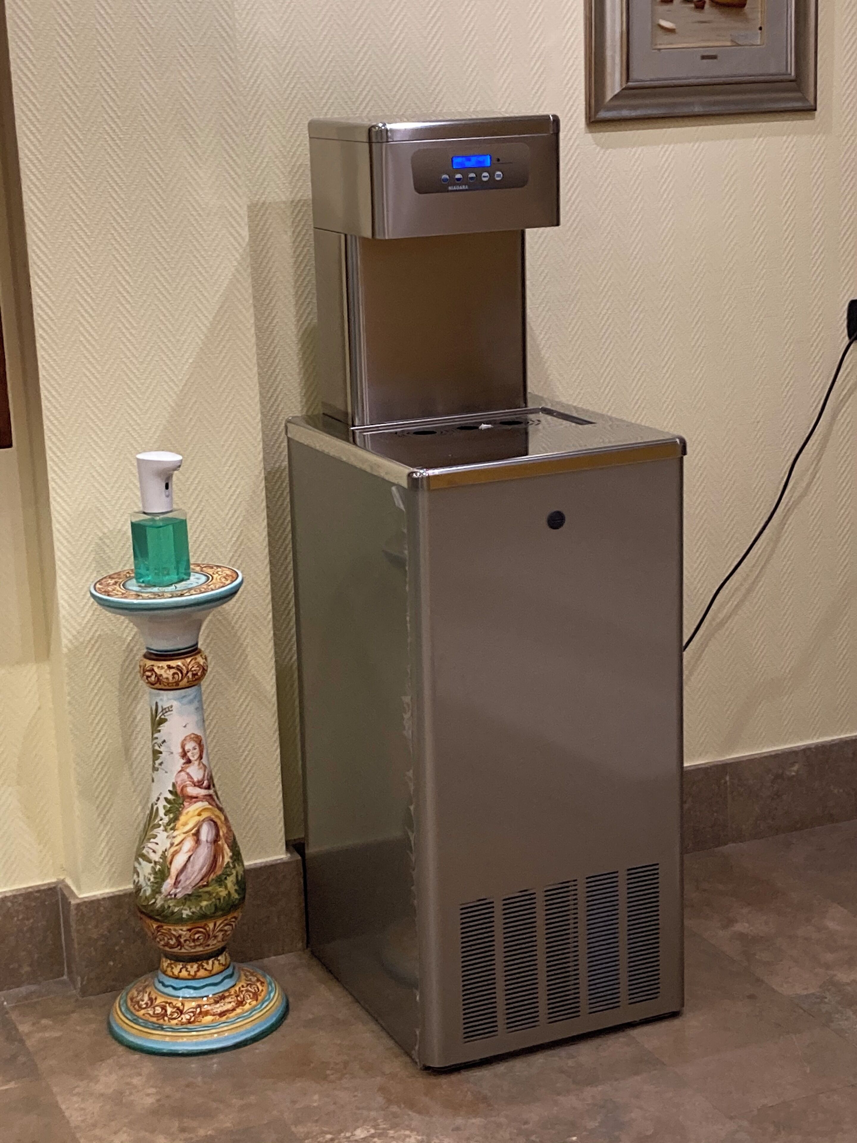 A water dispenser with a digital display, a decorative pump, and a tiled floor.