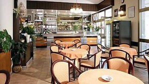A restaurant with round tables and chairs, a bar area, and a view of the street outside. - Residence Kriss (Deiva Marina)