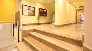 A hotel lobby with a marble staircase, a reception desk, and framed informational posters on the wall. - Residence Kriss (Deiva Marina)