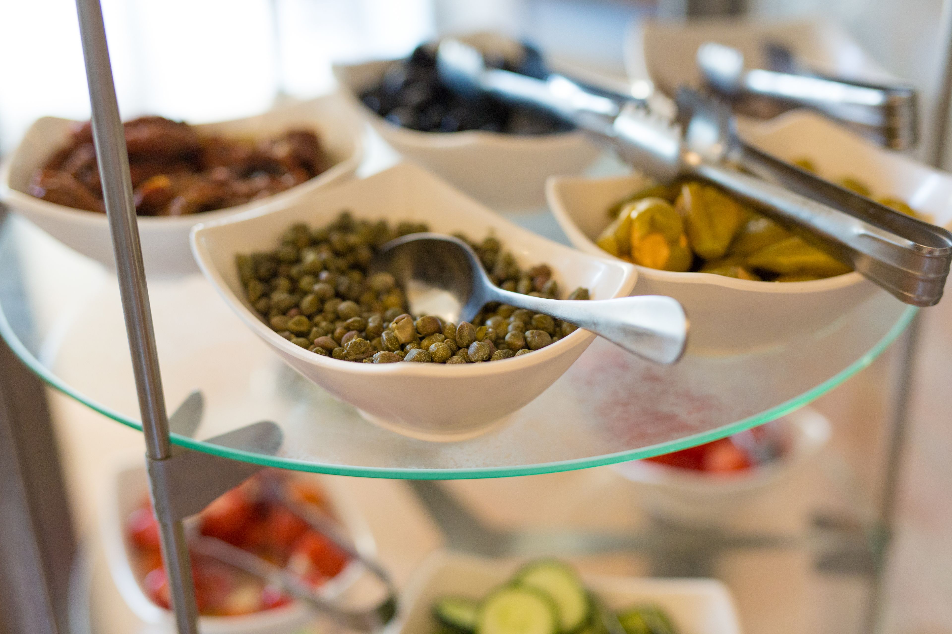 A buffet with various dishes including pickled vegetables, olives, and a bowl of green olives.