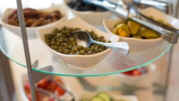 A buffet with various dishes including pickled vegetables, olives, and a bowl of green olives.