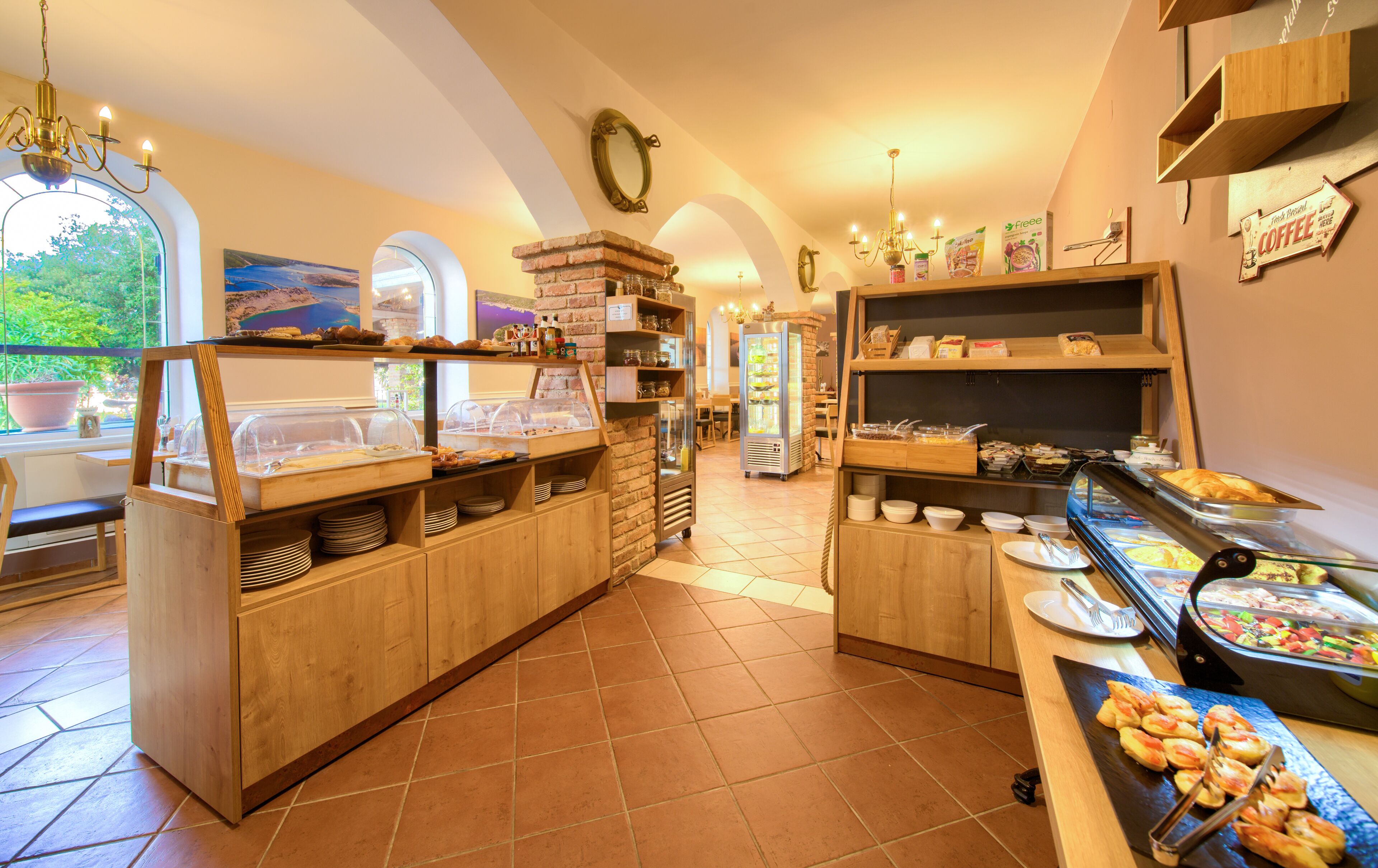Zona de desayuno tipo buffet con varias estaciones de comida, incluyendo una presentación de frutas y una estación de café.