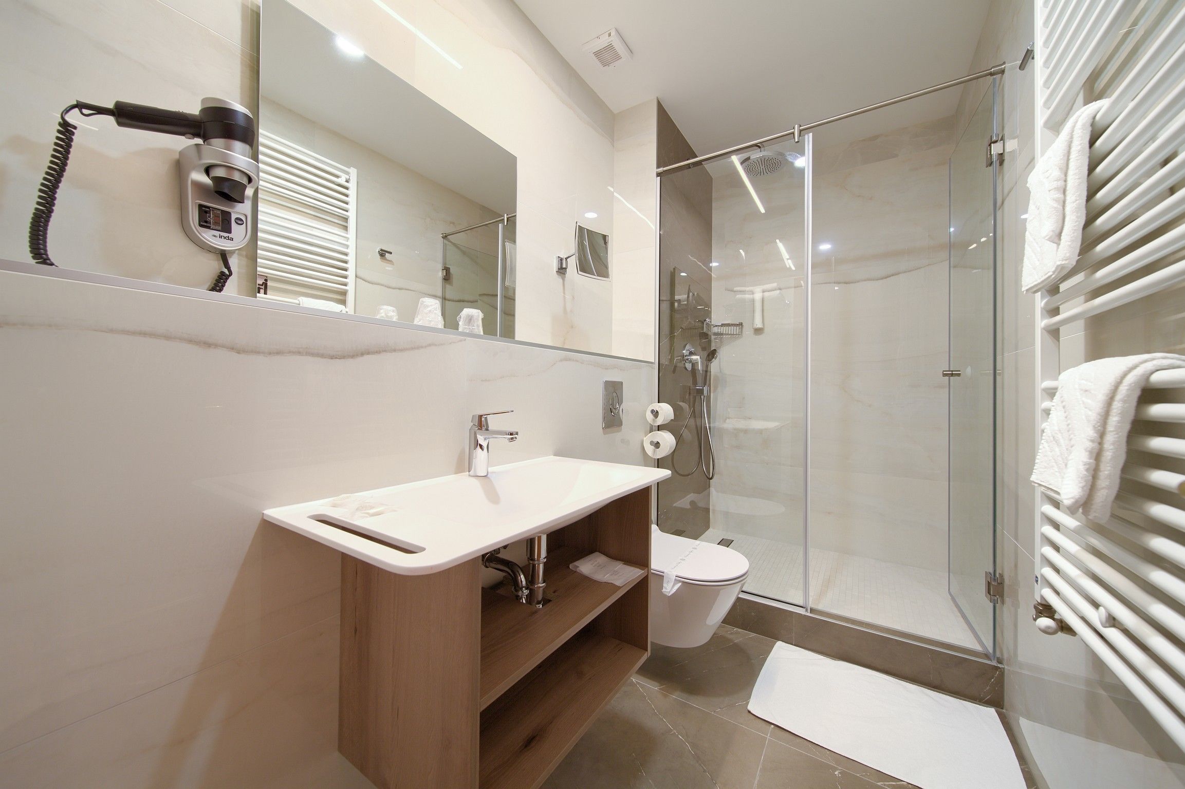 Une salle de bain moderne avec une douche à parois de verre, un lavabo blanc et un porte-serviettes.