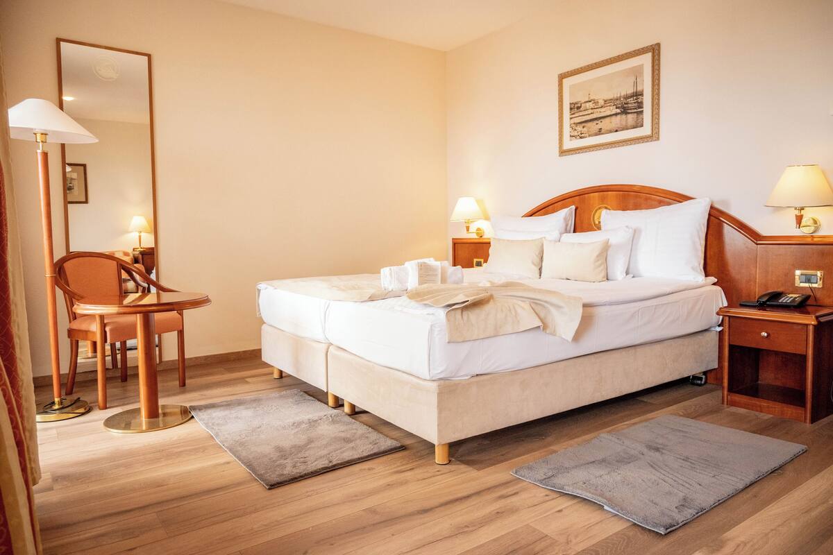 Una habitación de hotel con cama, mesitas de noche, una silla y un escritorio.