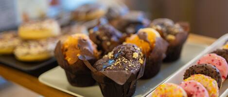 A tray of assorted pastries including chocolate muffins and decorated donuts.