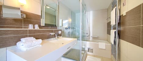 A modern bathroom with a large mirror, white sink, and glass shower enclosure.