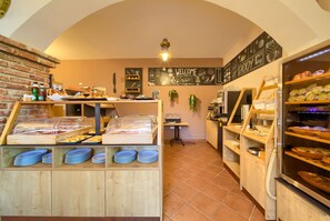 Una sección de panadería con vitrinas, estantes llenos de productos horneados y una pizarra con escritura.