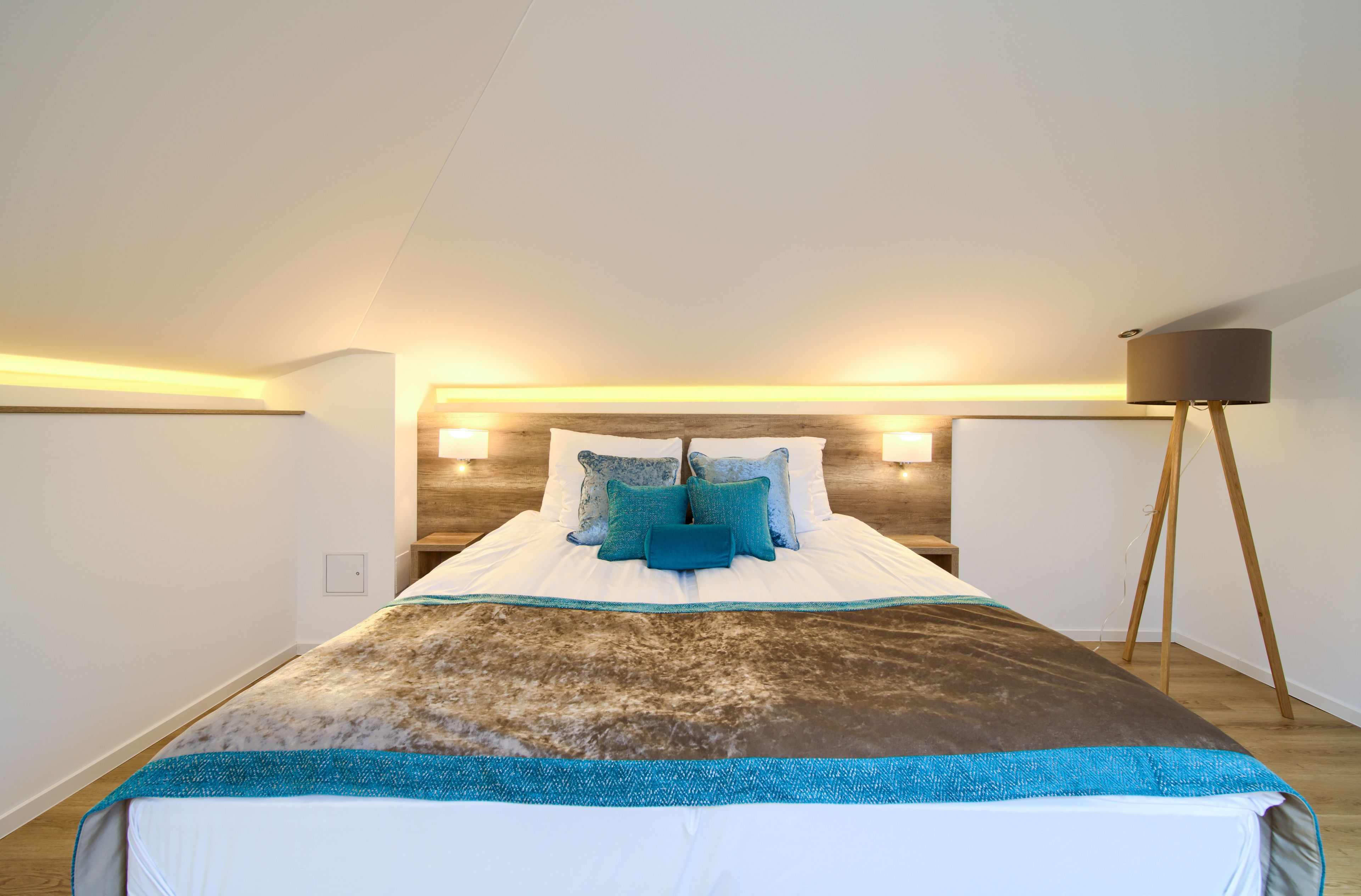 A bedroom with a bed, bedside lamps, and a floor lamp.