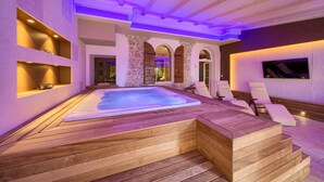 A spa area with a hot tub, wooden deck, stone walls, and seating. - Hotel Kanajt (Punat)