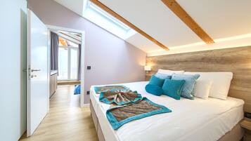 Un dormitorio con tragaluz, una cama con ropa de cama blanca y azul, y un cabecero de madera.