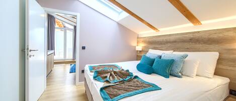 A bedroom with a skylight, a bed with white and blue bedding, and a wooden headboard.