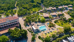 An aerial view of a resort with multiple buildings, a swimming pool, and lush greenery. - Hotel Kanajt (Punat)
