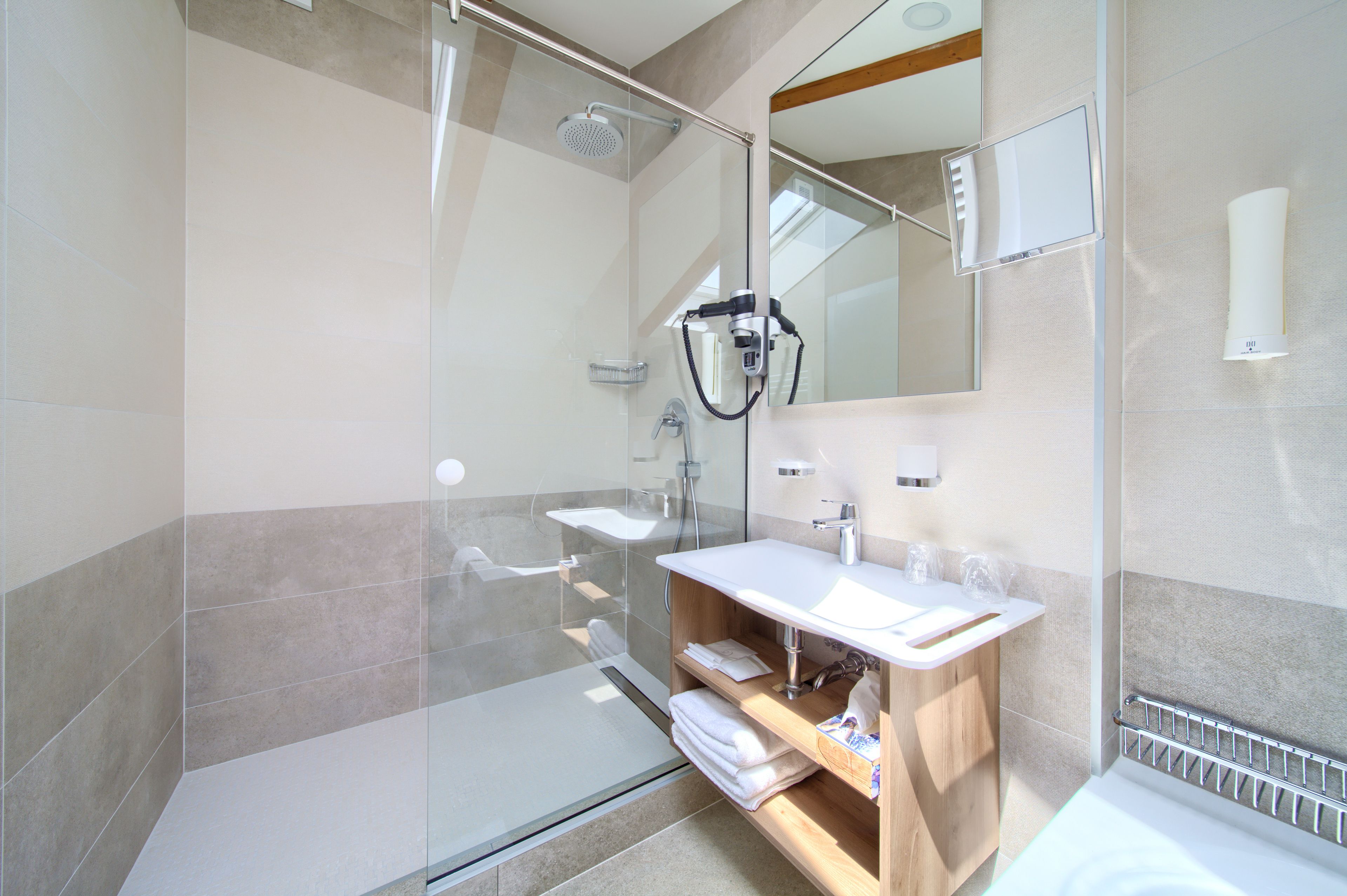 A modern bathroom with a glass-enclosed shower, a white sink, and a wooden vanity.