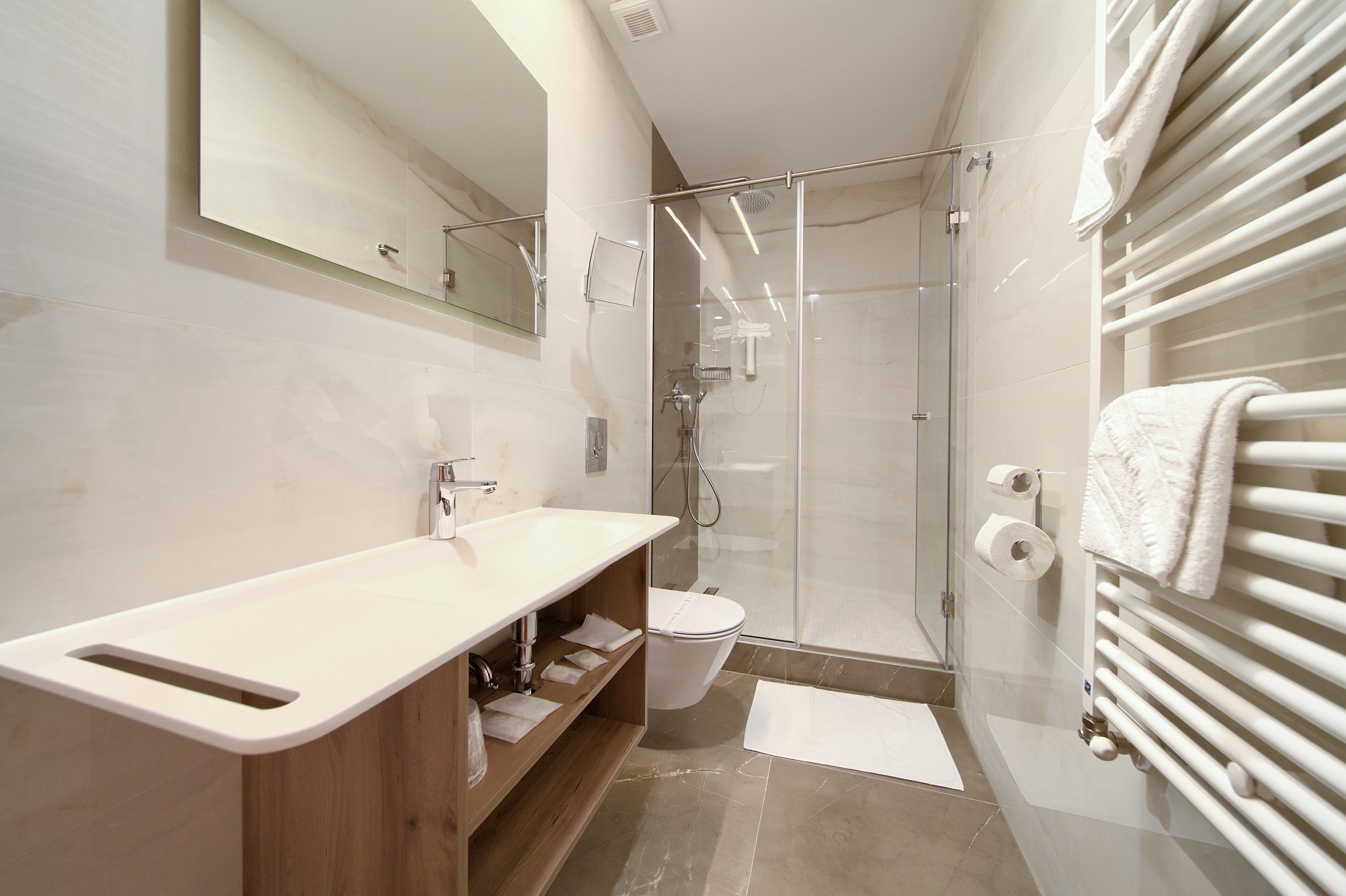 Un baño moderno con cabina de ducha de vidrio, un lavabo blanco y un perchero para toallas.