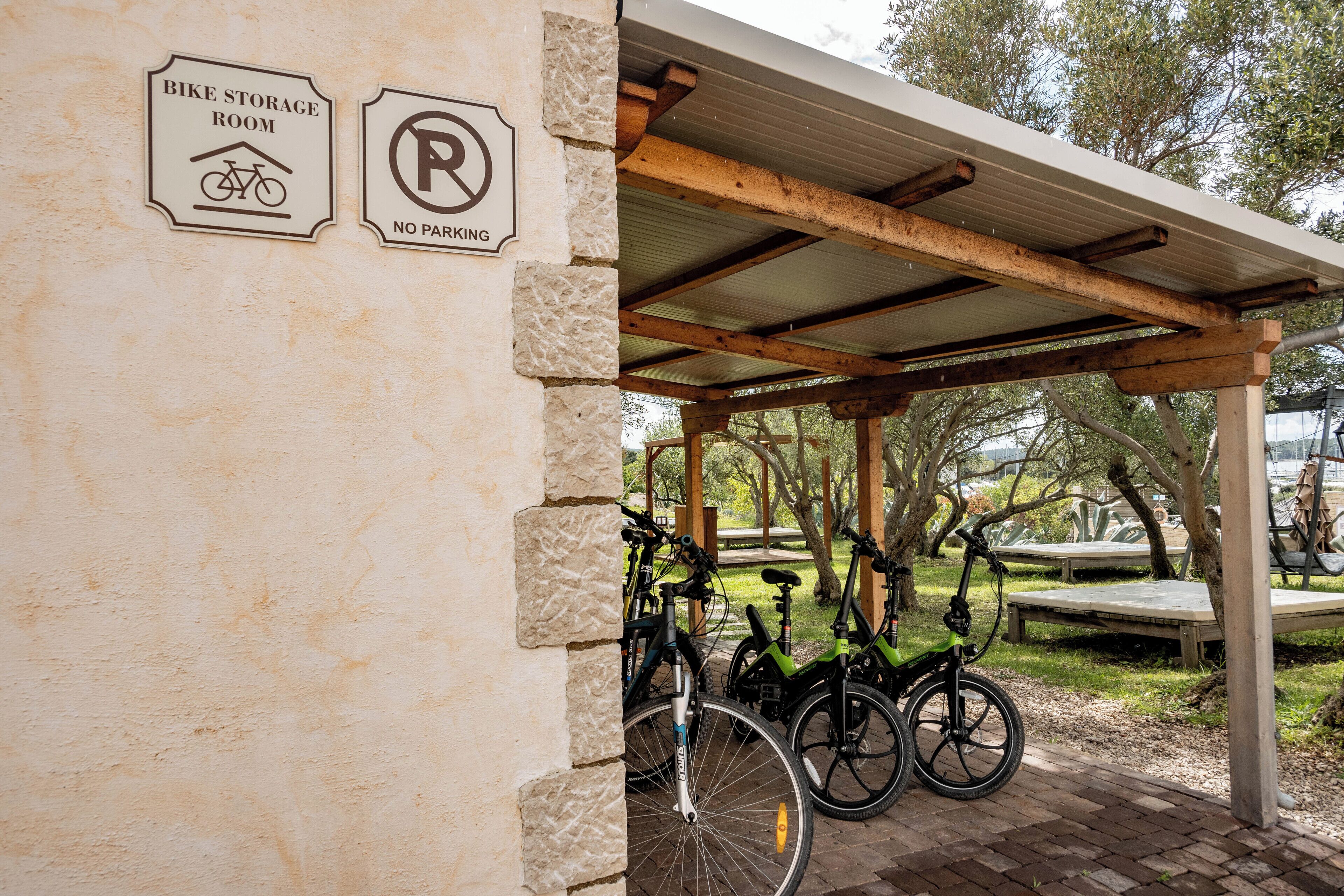 Una sala para guardar bicicletas y un cartel de prohibido estacionar en una pared del edificio.