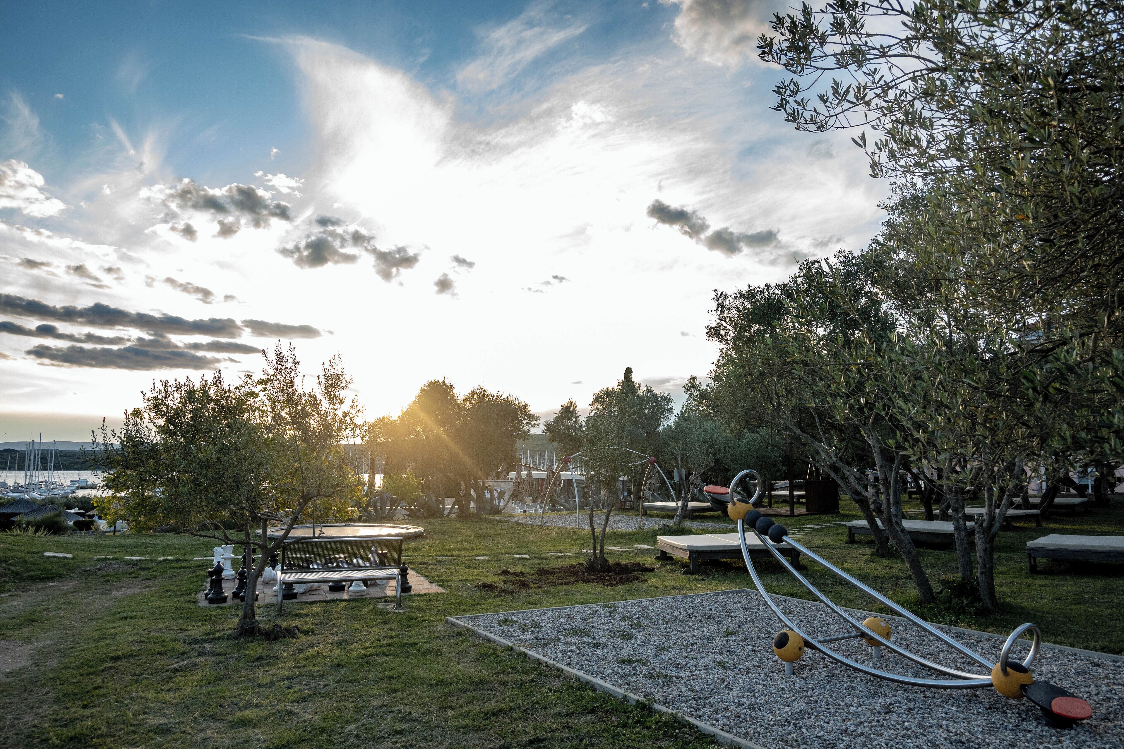 Un parque al aire libre con equipo de ejercicio, bancos y árboles.