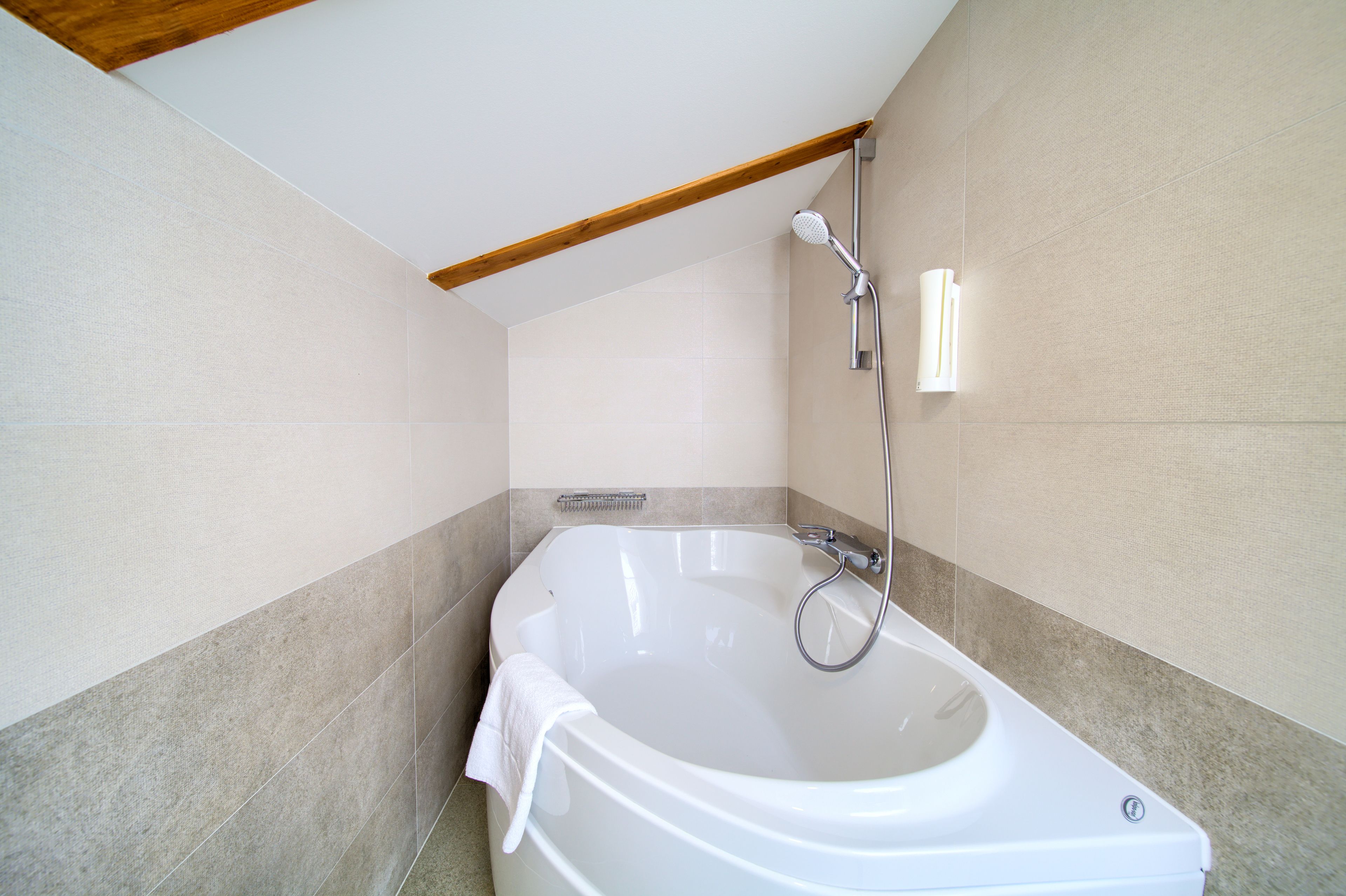 A modern bathroom with a freestanding bathtub, a showerhead, and a towel hanging on the tub.
