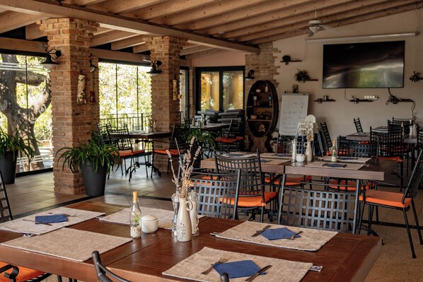 A restaurant with brick walls, wooden beams, and multiple tables with orange chairs. - Hotel Kanajt (Punat)